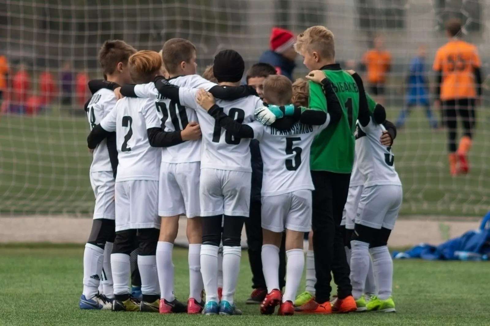 A youth football team in a huddle on the pitch